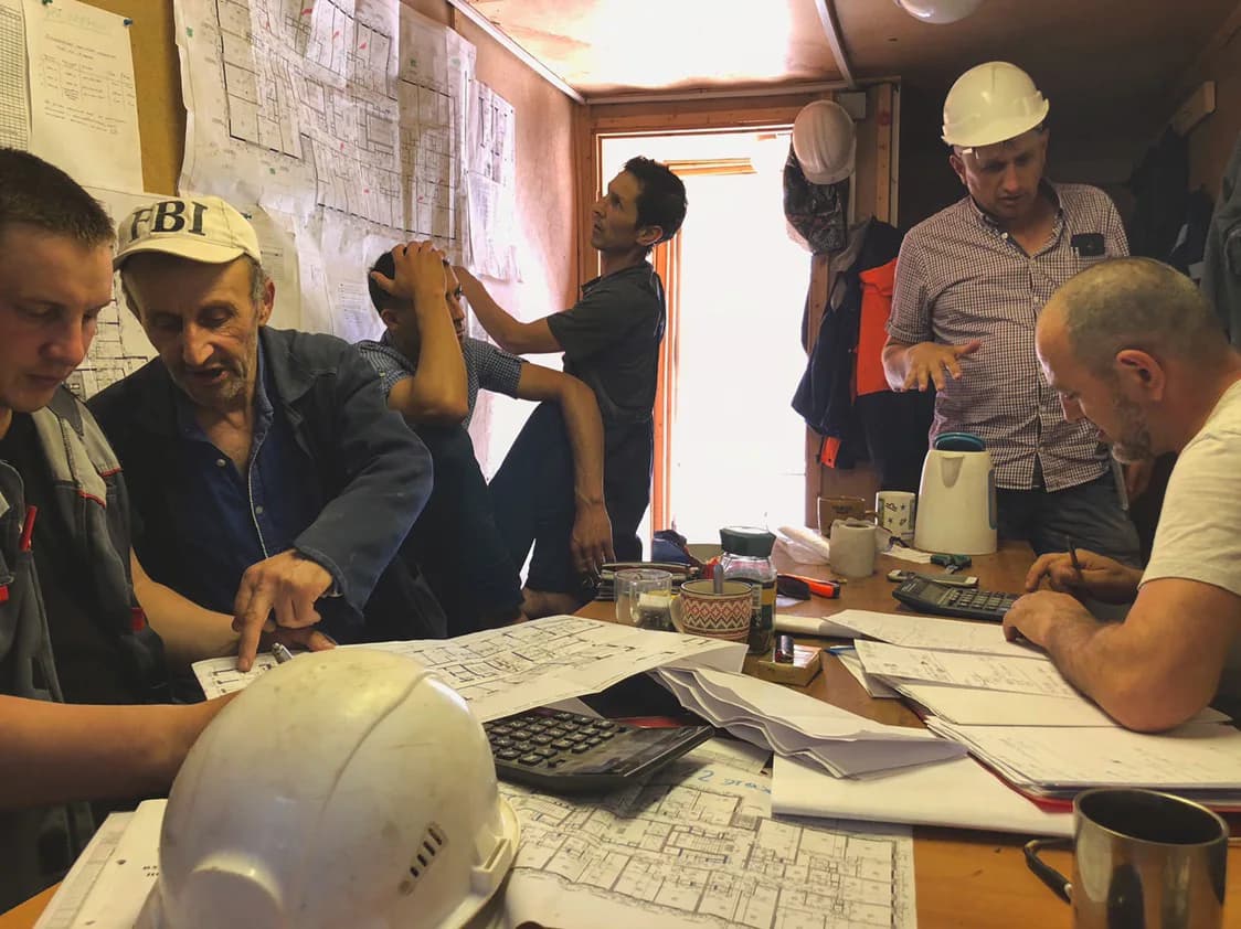 Eugene Prudchenko and a construction team reviewing technical plans in a site office in Russia.