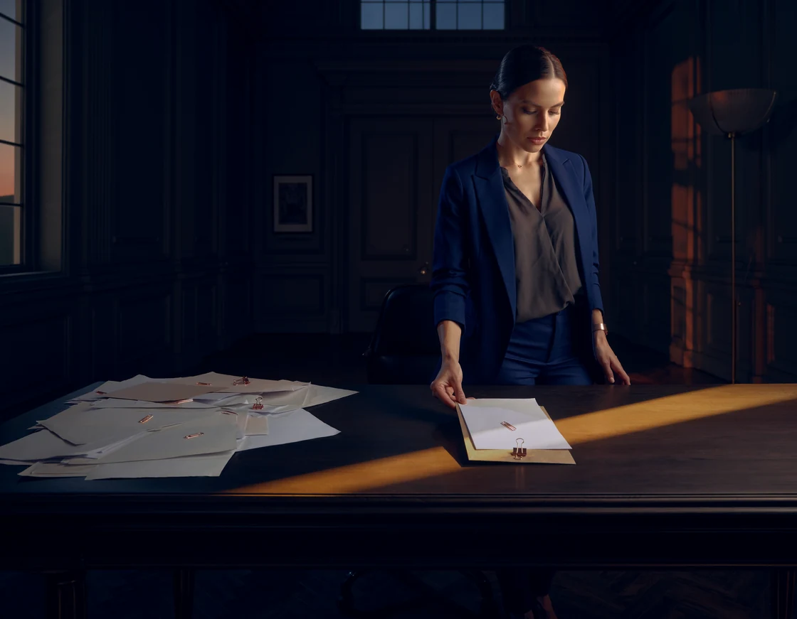 A professional organizing scattered papers into a prepared communication.