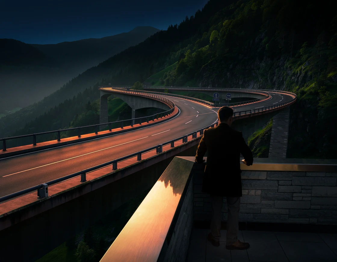 A person overlooking a curving mountain bridge with diverging routes.